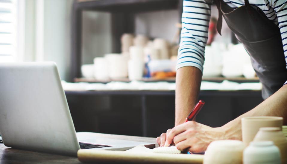 Person skriver anteckningar vid en laptop