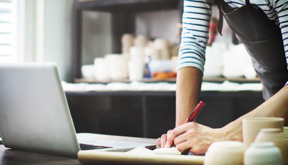 Person skriver anteckningar vid en laptop